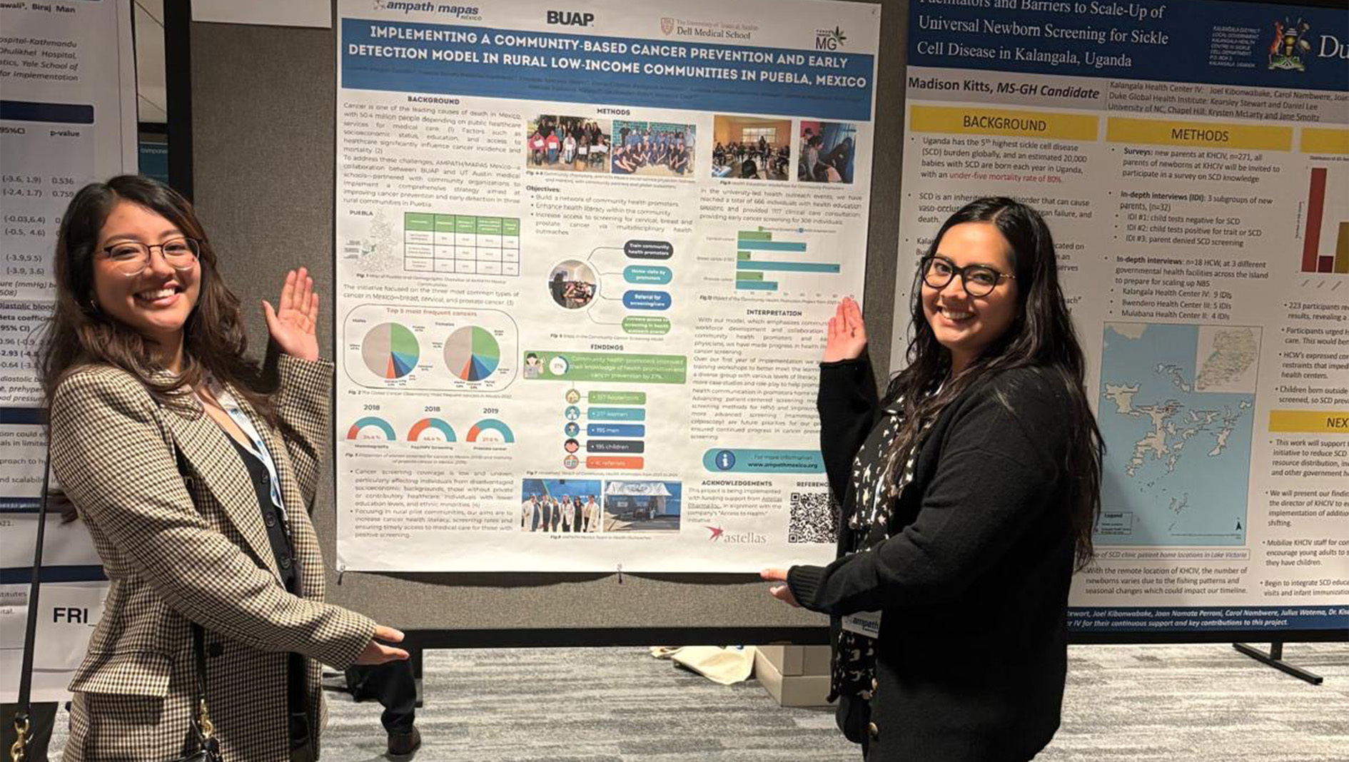 Two women smile and stand by their academic poster.