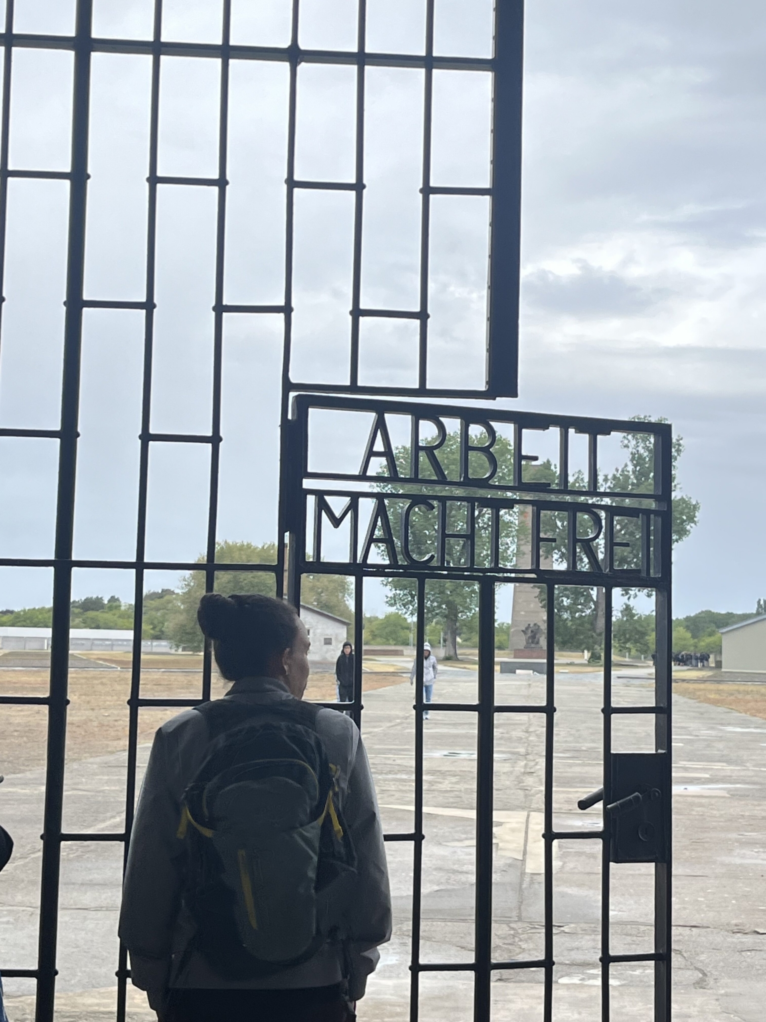 A Dell Medical School student stands at and looks through the gates of the Sachsenhausen concentration camp.